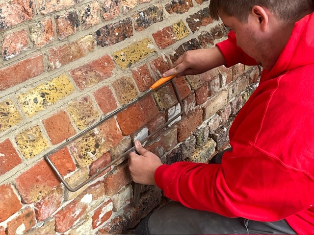 Leerlingen van VTI Brugge helpen met de restauratie van de abdijmuur.